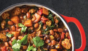 Aerial view of a pot of chili, with red handle of the pot on the right side.