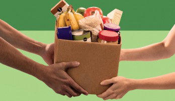 Two sets of hands holding a medium sized box of food.