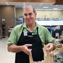 Publix Associate Joe Timmons in uniform smiles for the camera while holding a shopping bag.