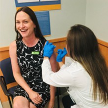 Publix Associate Kathy Leonard smiles as she gets her flu shot in her left arm.