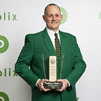 Michael Millien CLT Division store manager, holds his award dressed in his best green blazer