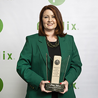 Kelly Wilson JAX Division store manager, holds his award dressed in her best green blazer