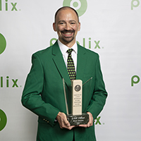 Nick Abiusi MIA Division store manager, holds his award dressed in his best green blazer